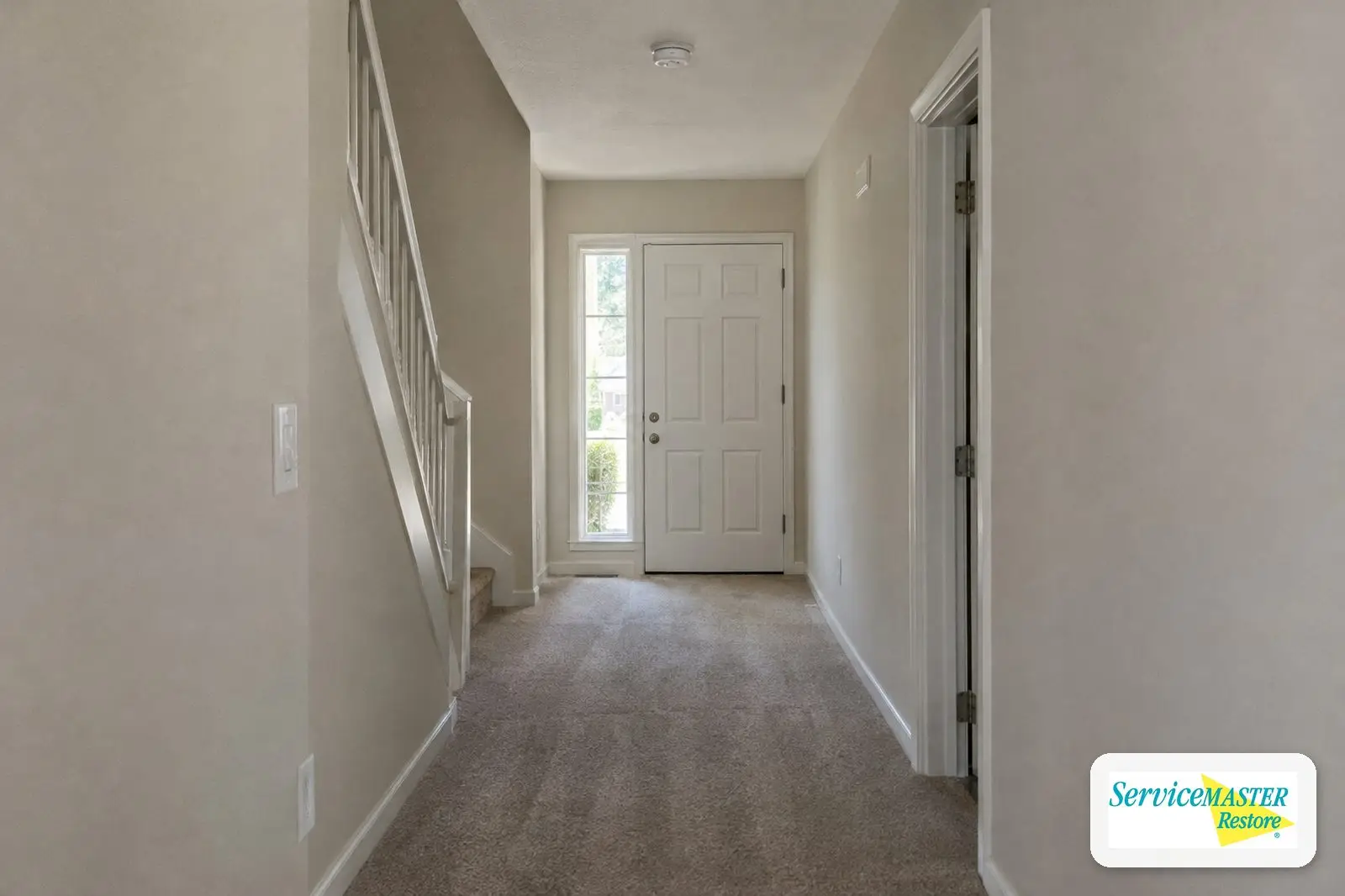 Clear hallway leading to the front door with a ceiling smoke alarm, showing a safe exit path