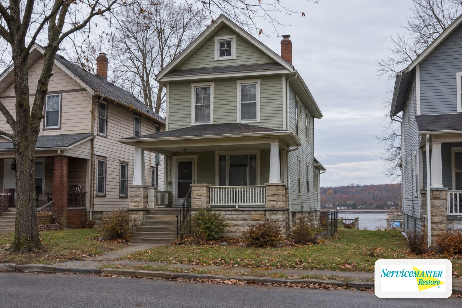 Older two-story frame house with a stone foundation and front porch on a residential street